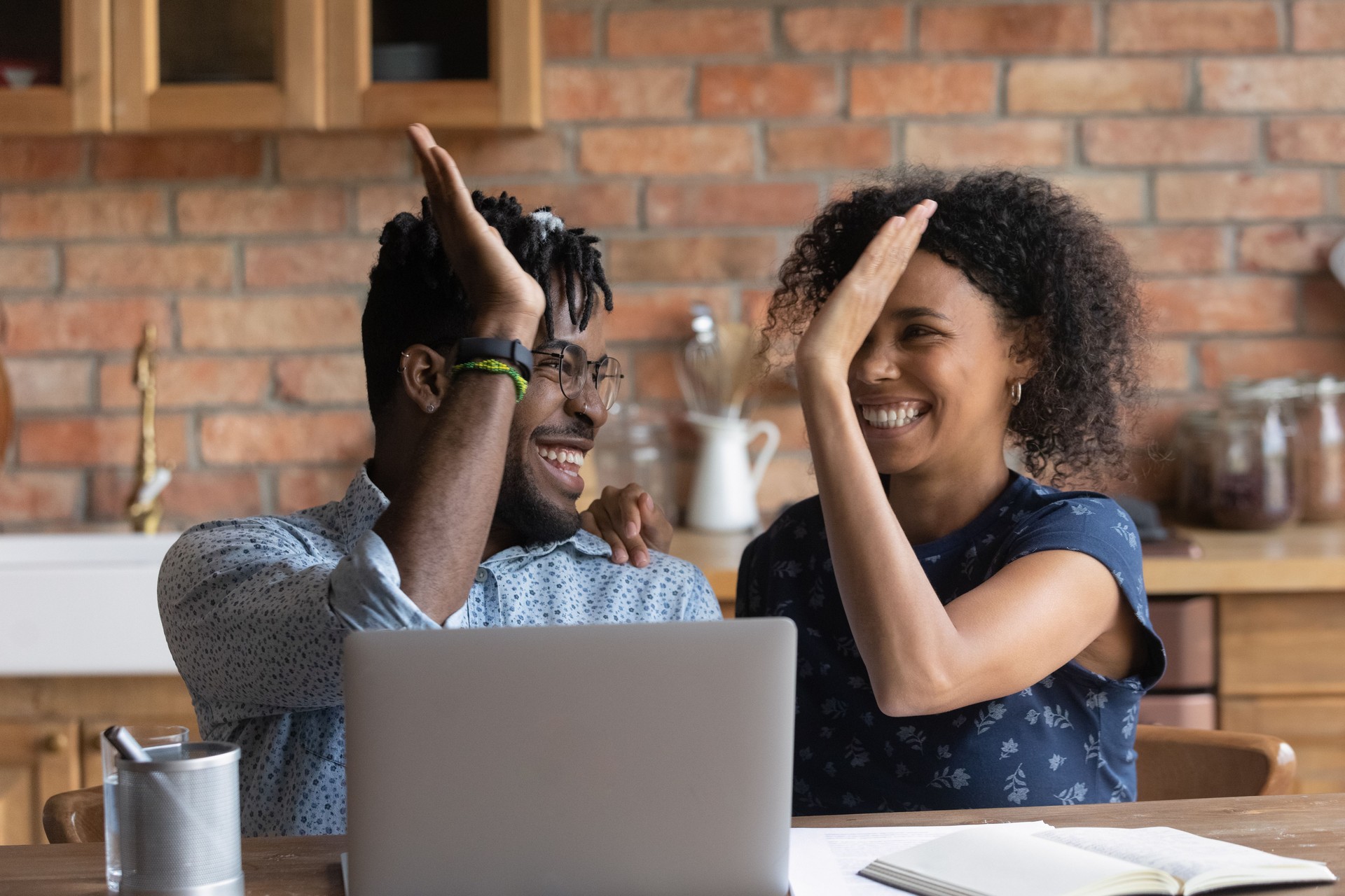Happy excited Black mixed race couple celebrating success at laptop